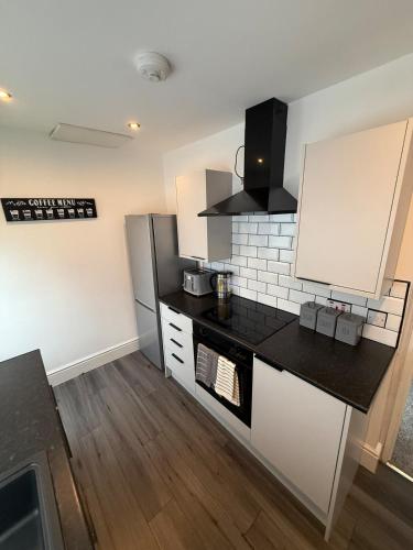 a kitchen with white cabinets and a black counter top at ResiLets - Stanley House - Large, Modern 3 Bed - NEW! in Blythe