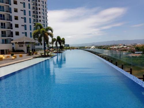 a large swimming pool with palm trees and a building at Mactan Newtown Boulevard 8 Deluxe Tower One in Punta Engaño
