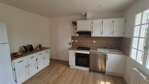a kitchen with white cabinets and a stove top oven at Gîte Au Cœur des Châteaux in Cheverny