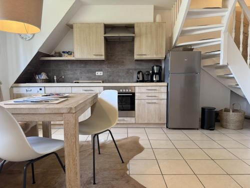 a kitchen with a wooden table and white chairs at Strand-Lug Wenningstedt in Wenningstedt