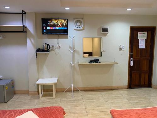 a room with a tv on the wall and a table at Miracle Gallery Hotel in Makkasan