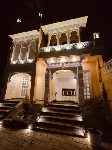 a house with lights on the front of it at night at The Rajshahi Vilas in Udaipur