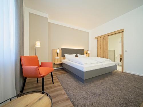 a bedroom with a bed and a chair and a mirror at Hotel Adler in Mainz