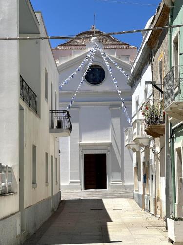 an alley with a white building with a string of lights at Il Maestralino, nice apartment with courtyard in Calasetta