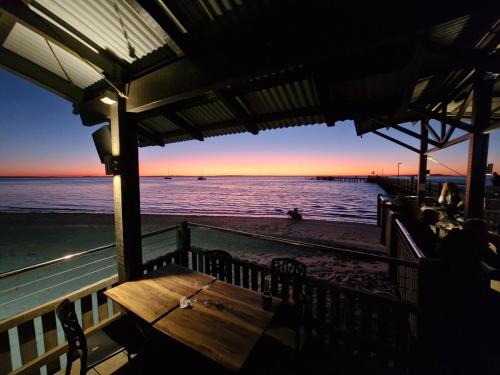 a picnic table on the beach at sunset at Villa Cooloola Calm - C709, Kingfisher Bay Resort in Kingfisher Bay