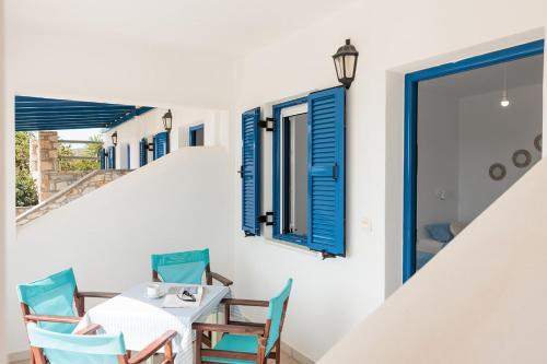 a dining room with blue windows and a table and chairs at Aurea Blu Studio 04, enjoy peace, quiet, sand and sea in Aliko Beach