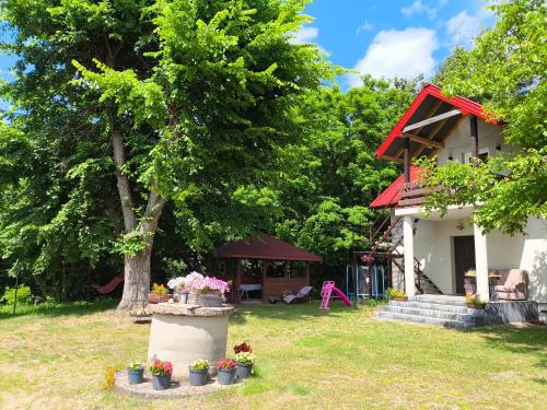 a house with a tree and flowers in a yard at Agroturystyka Zacisze nad Pilicą in Stromiec