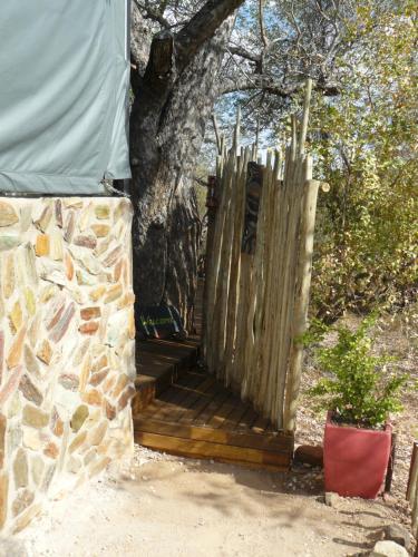a wooden porch with a fence next to a tree at Tjhora Sunset Cottage in Cambridge