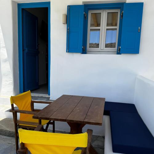 a wooden table and chairs in front of a blue door at Cordiale Mykonos in Ornos