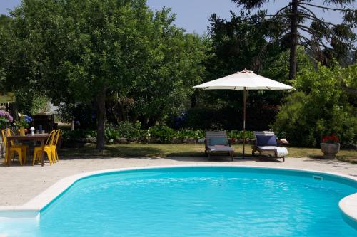 a swimming pool with a table and an umbrella at Casa das Mós in Amarante