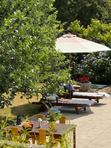 a patio with tables and chairs and an umbrella at Casa das Mós in Amarante