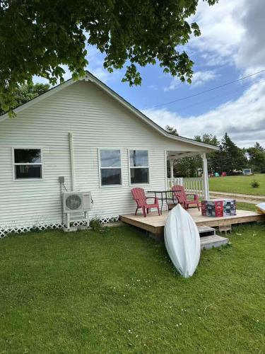 Casa con terraza con 2 sillas y mesa en Sea breeze Retreat-3-bedroom watterfront cottage, en Stanhope