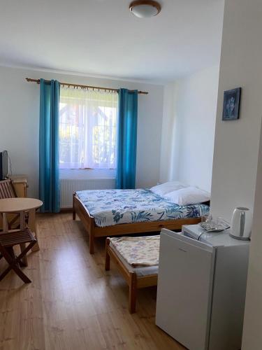 a bedroom with two beds and a table and a window at Dom Wczasowy Aleksandra in Niechorze