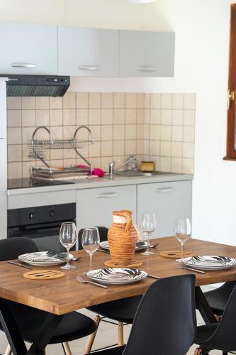 a kitchen with a wooden table with wine glasses at maison climatisée fibrée 2 chambres à 9 min à pieds d'une grande plage in Venzolasca