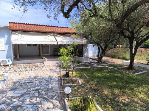 a yard with trees and a house with a stone patio at SunRay Halkidiki Home & Garden in Kalyves Poligirou