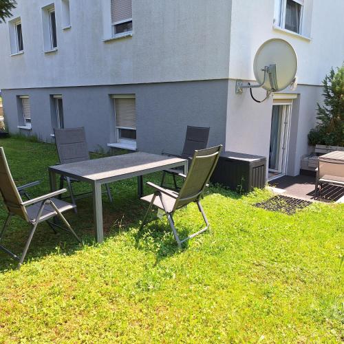a picnic table and chairs in the grass in front of a building at Schöni´s Zimmer in Abstatt