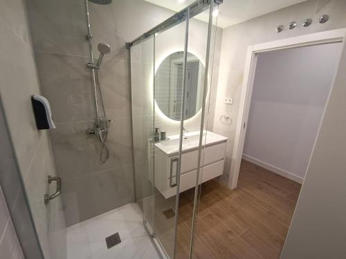 un bagno con doccia, lavandino e specchio di Apartamentos BONDELA a Madrid