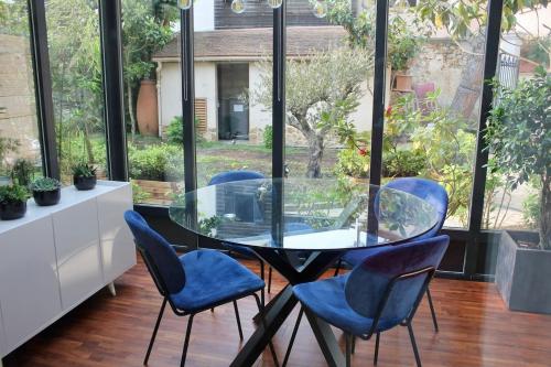 une table et des chaises en verre dans une pièce avec fenêtres dans l'établissement Duplex-Saint-Rémy-lès-Chevreuse, à Saint-Rémy-lès-Chevreuse