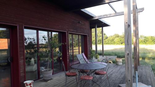 a patio with a table and chairs on a deck at Maison bois à la campagne in Marnay