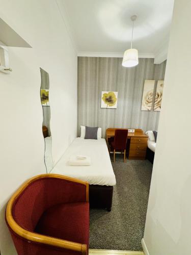 a room with a bed and a chair and a desk at Carlton Court Hotel Eastbourne in Eastbourne