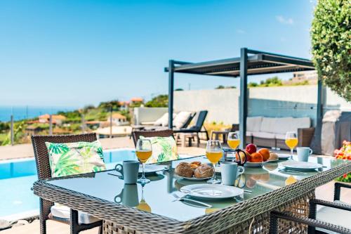 a table with food and drinks on a patio at Villa Pinheira III heated pool in Calheta