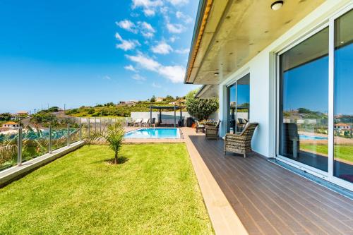 a house with a deck with a view of a swimming pool at Villa Pinheira III heated pool in Calheta