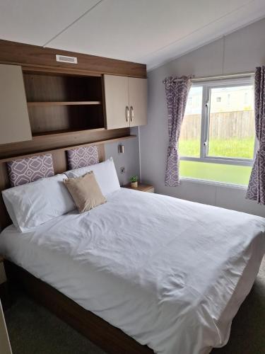 a bedroom with a large white bed and a window at Northern Lights in Lossiemouth