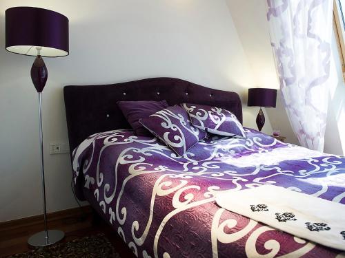 1 dormitorio con 1 cama con edredón morado y 2 lámparas en Lake View Villa, en Ełk