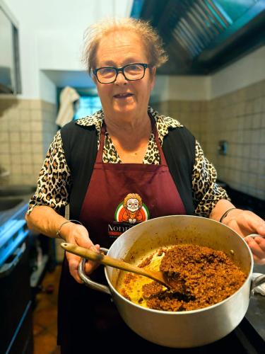 a woman holding a pot of food in a kitchen at Nonna Nara Bed & Breakfast in Grosseto