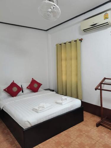 a bedroom with a bed with red pillows on it at PHAI GUESTHOUSE in Luang Prabang