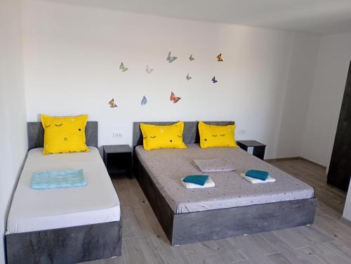 two beds in a room with yellow and blue pillows at Casa din Deal in Corbu