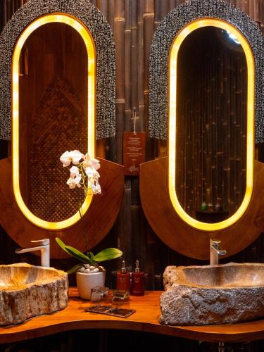 a bathroom with two sinks and two mirrors at Ulaman Eco Luxury Resort in Tabanan