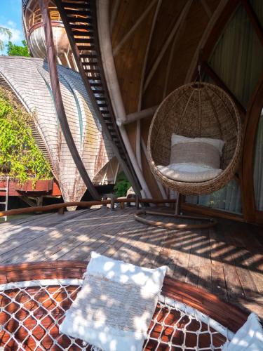 a porch with a rattan chair on a patio at Ulaman Eco Luxury Resort in Tabanan