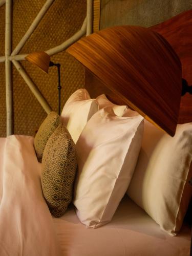 a bed with white pillows and a lamp on it at Ulaman Eco Luxury Resort in Tabanan