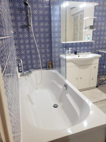 La salle de bains est pourvue d'une baignoire blanche et de carrelage bleu. dans l'établissement Agréable maison avec vue panoramique, à La Bourboule