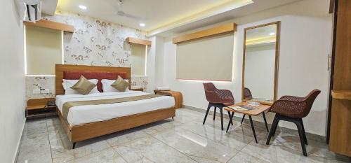 a bedroom with a bed and a table and chairs at Hotel Nova Venus in Rajkot
