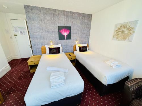 a hotel room with two beds with white sheets at Carlton Court Hotel Eastbourne in Eastbourne