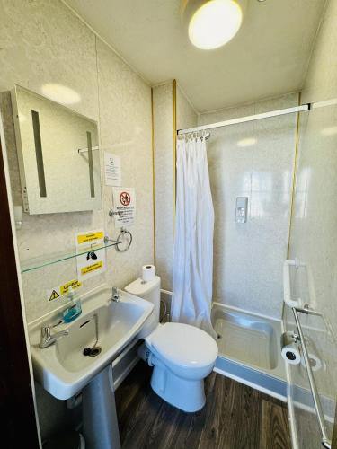 a bathroom with a toilet and a sink and a shower at Carlton Court Hotel Eastbourne in Eastbourne