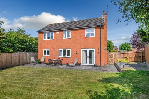a red brick house with a patio in a yard at The Family & Contractor Haven in Shepshed