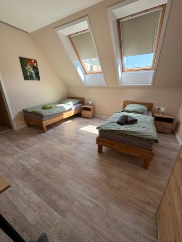 two beds in a room with two windows at Herberge in der Orangerie auf dem Schlossgut Altlandsberg in Altlandsberg