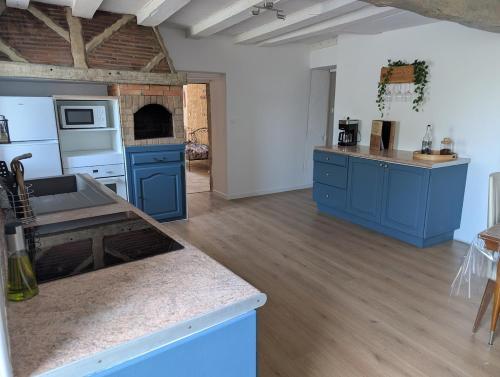 une cuisine avec des armoires bleues et un comptoir dans l'établissement La Maison du Bourg, à Saint-Vivien