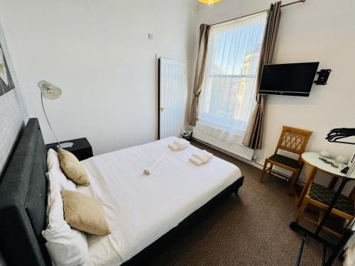 a bedroom with a bed and a desk and a window at Carlton Court Hotel Eastbourne in Eastbourne