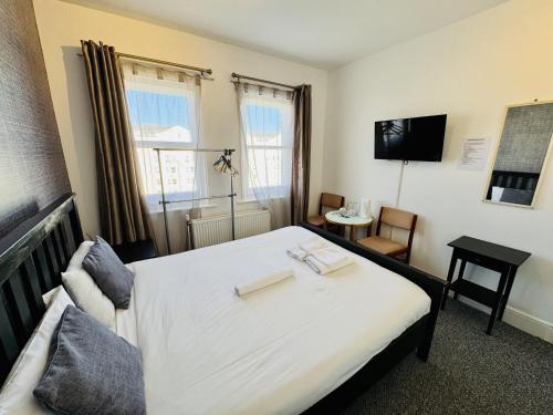 a hotel room with a bed and a television at Carlton Court Hotel Eastbourne in Eastbourne