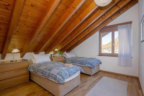 two beds in a room with wooden ceilings at St Martin Loft Apartment in Täsch