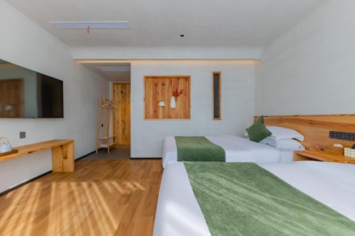 XintanHuangshan Tunxi Shangjiexing Riverview Resort Hotel的一间有两张床和一台平板电视的酒店房间