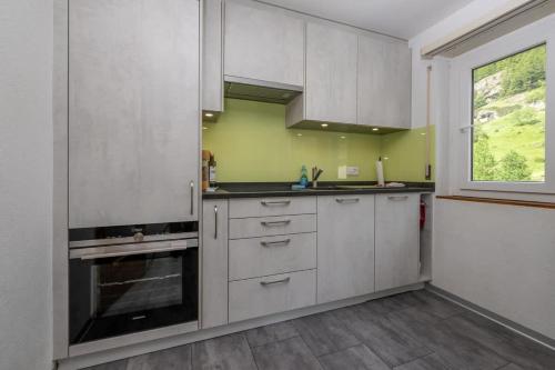 a kitchen with white cabinets and a window at Breithorn View in Täsch