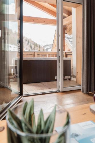 a room with a large window and a table with a plant at Montresor Hotel Pfeldererhof in Pfelders
