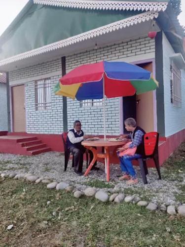 two people sitting at a table with an umbrella at Poddar Retreat in Mal bazar