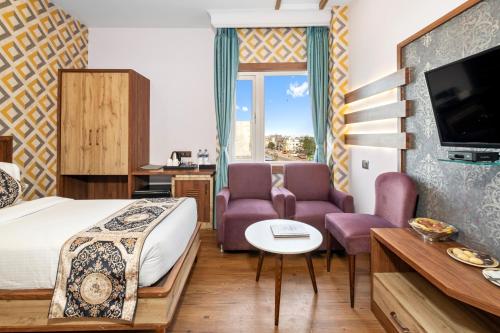 a hotel room with a bed and two purple chairs at PRIME LAND in Varanasi