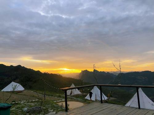 a view of a sunset from a deck with tents at Sunrise Ha Giang Camping An Introspective Stay in Suy Tung Su